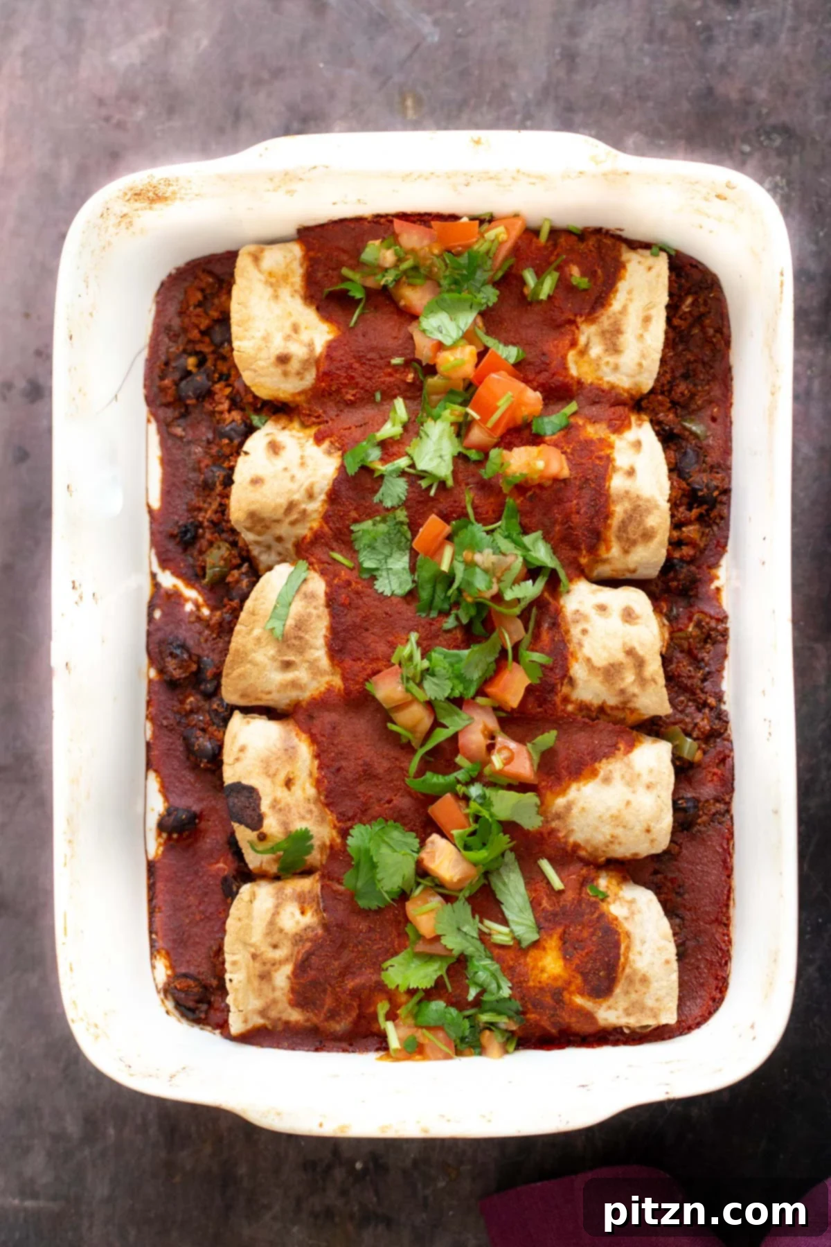 Plant-Powered Enchiladas: Zesty Cauliflower-Bean Filling & Homemade Sauce 22 A close-up of two individual vegan enchiladas, filled with cauliflower taco meat and topped with generous enchilada sauce and fresh cilantro.