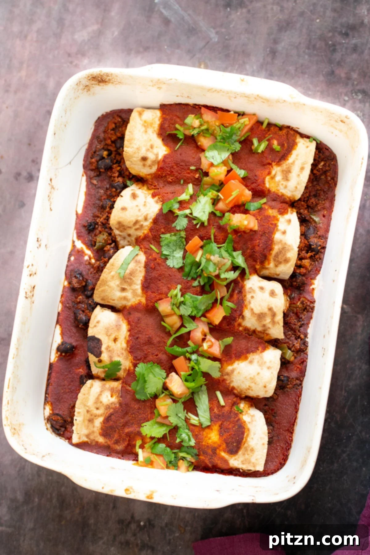 Vegan enchiladas with cauliflower taco meat and homemade enchilada sauce, beautifully arranged in a white casserole dish, ready to be served.