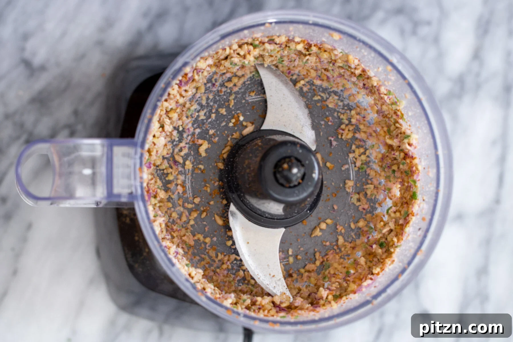 The food processor with the initial cauliflower taco meat mixture, showing the coarse texture after the first blend.