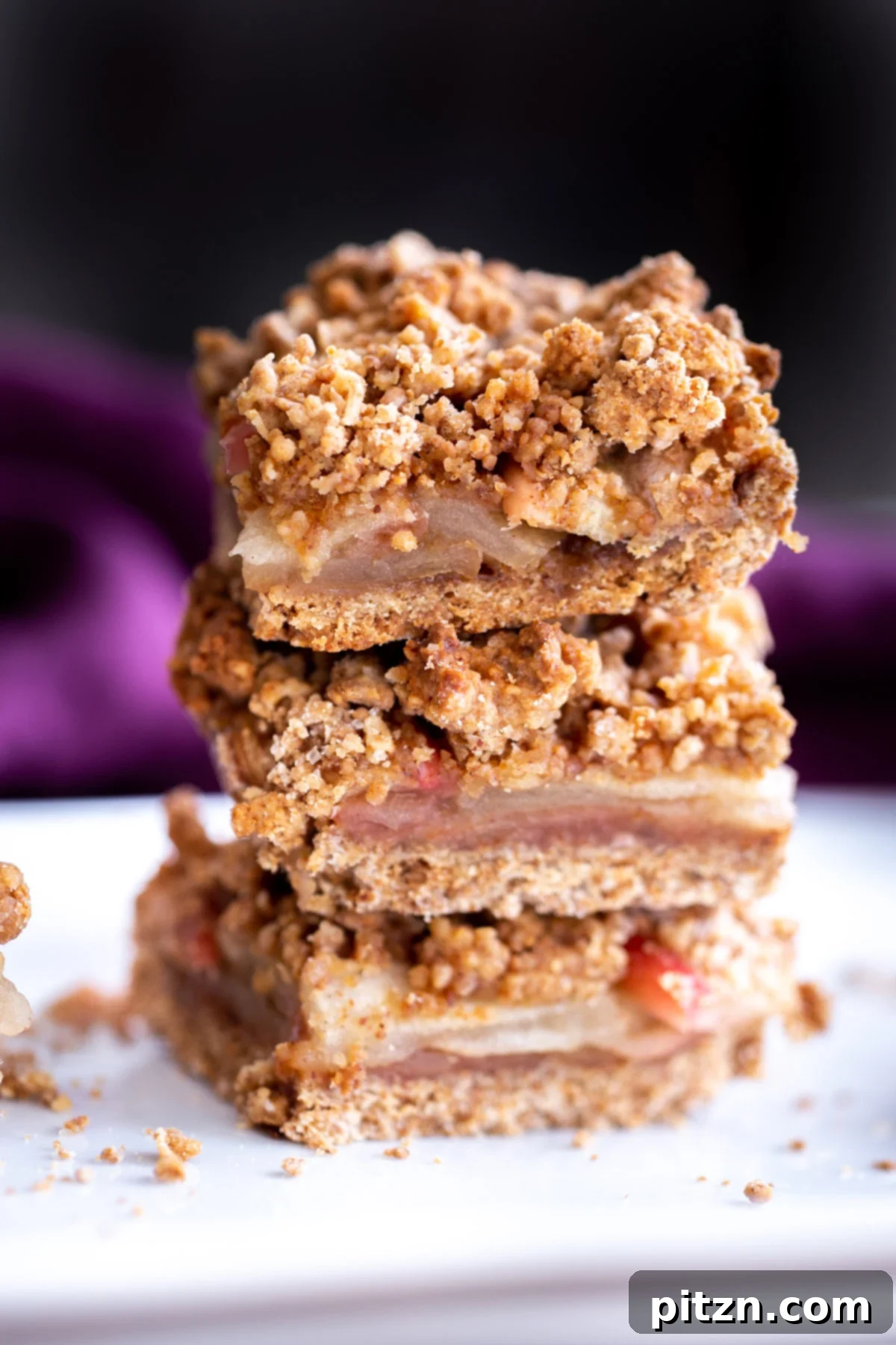 stacked vegan apple pie bars against a black background 