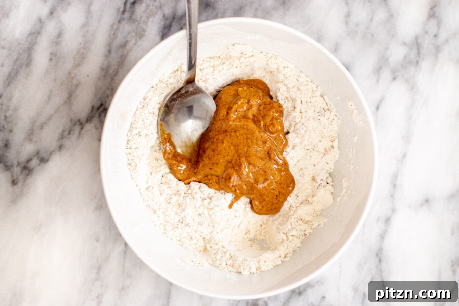 almond butter being mixed into dry crumble crust ingredients