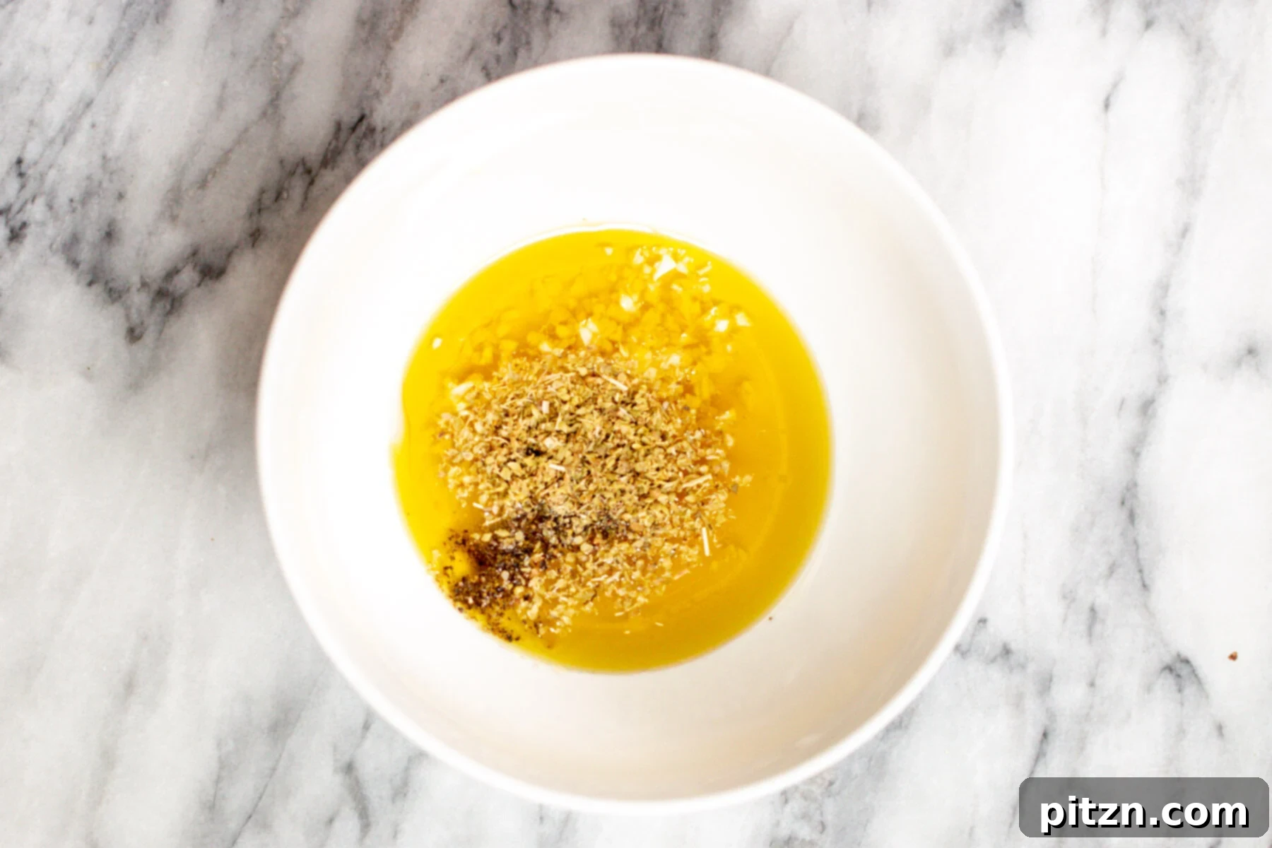 Mediterranean dressing ingredients being combined in a small white dish