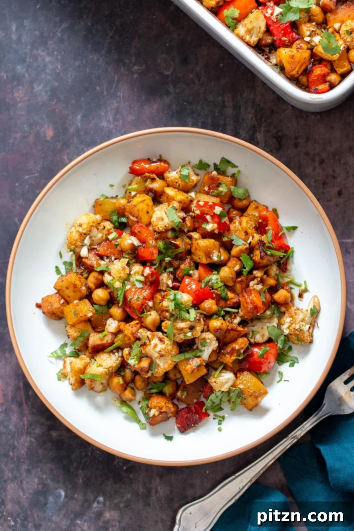 oven roasted root veggies and chickpeas served on a white plate sprinkled with cilantro