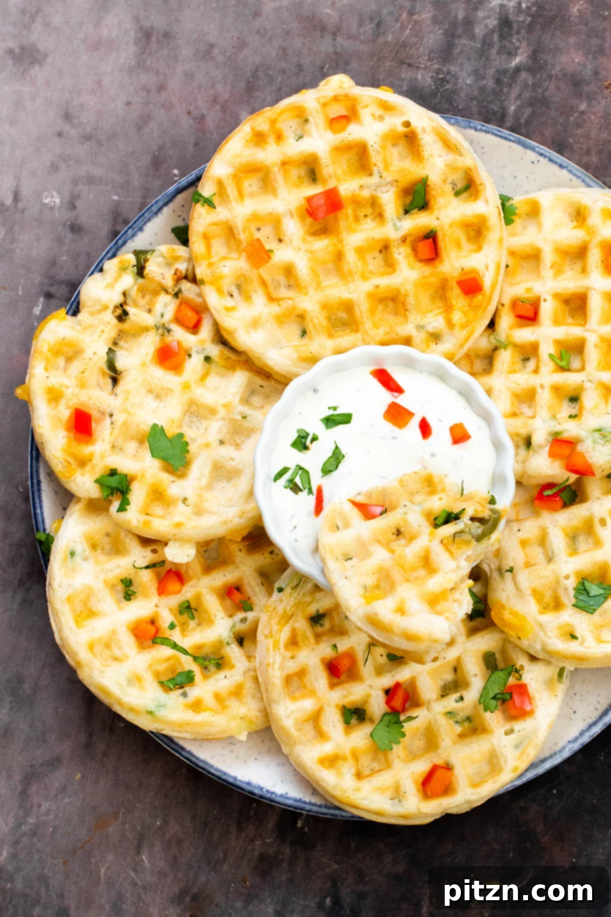 Kickin' Vegan Cheddar Jalapeno Waffles 12 a plate of vegan savory jalapeno cheddar waffles with a dip in the middle and a piece of waffle dipped in the dip dish