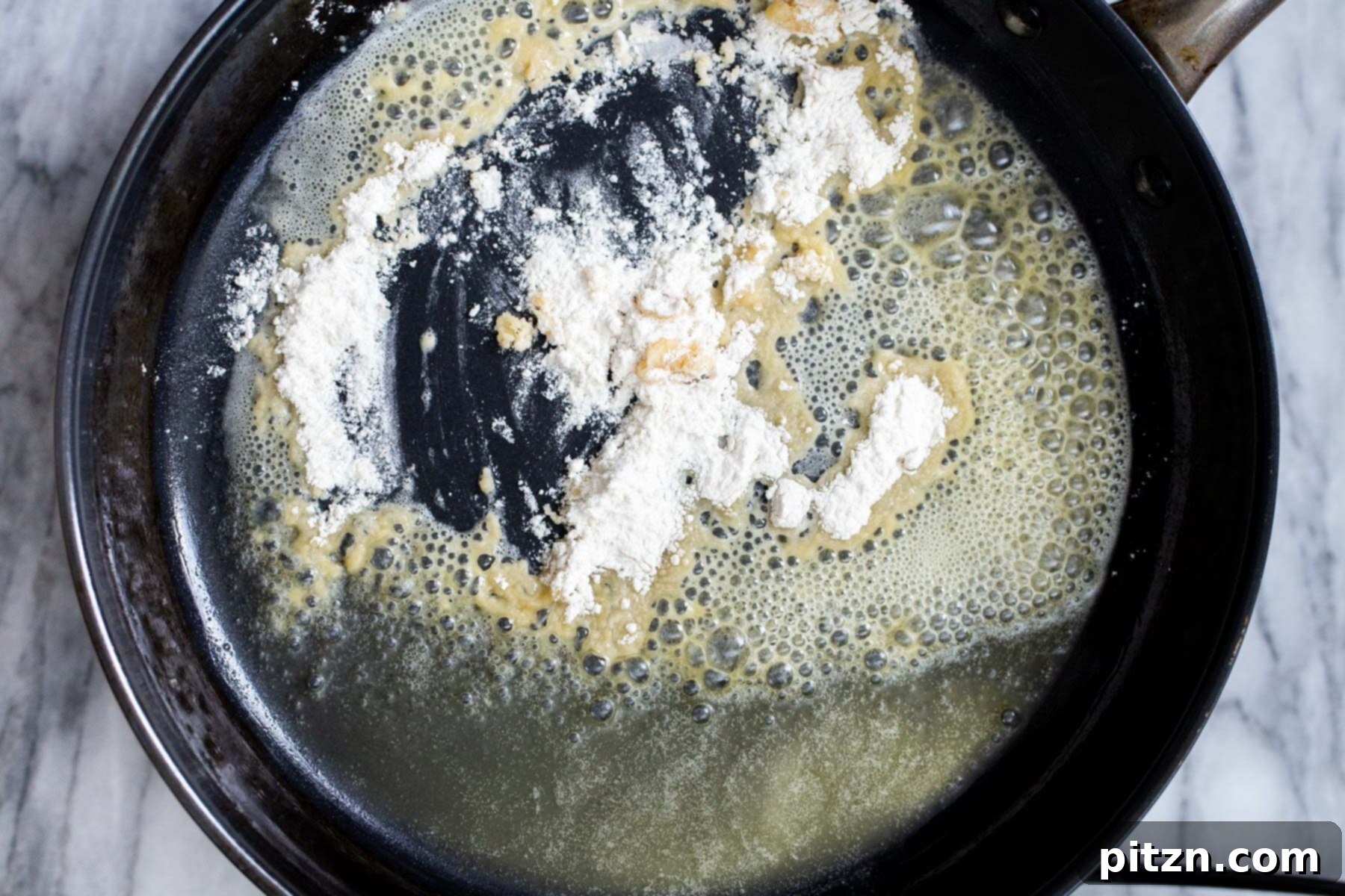 Swedish Plant-Ball Perfection 13 Melted vegan butter and flour beginning to form a roux in a black sautéing pan.