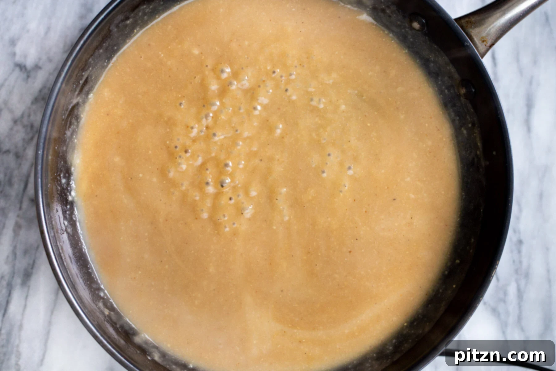 Swedish Plant-Ball Perfection 16 Rich and savory vegan mushroom gravy simmering in a sautéing pan, infused with herbs.