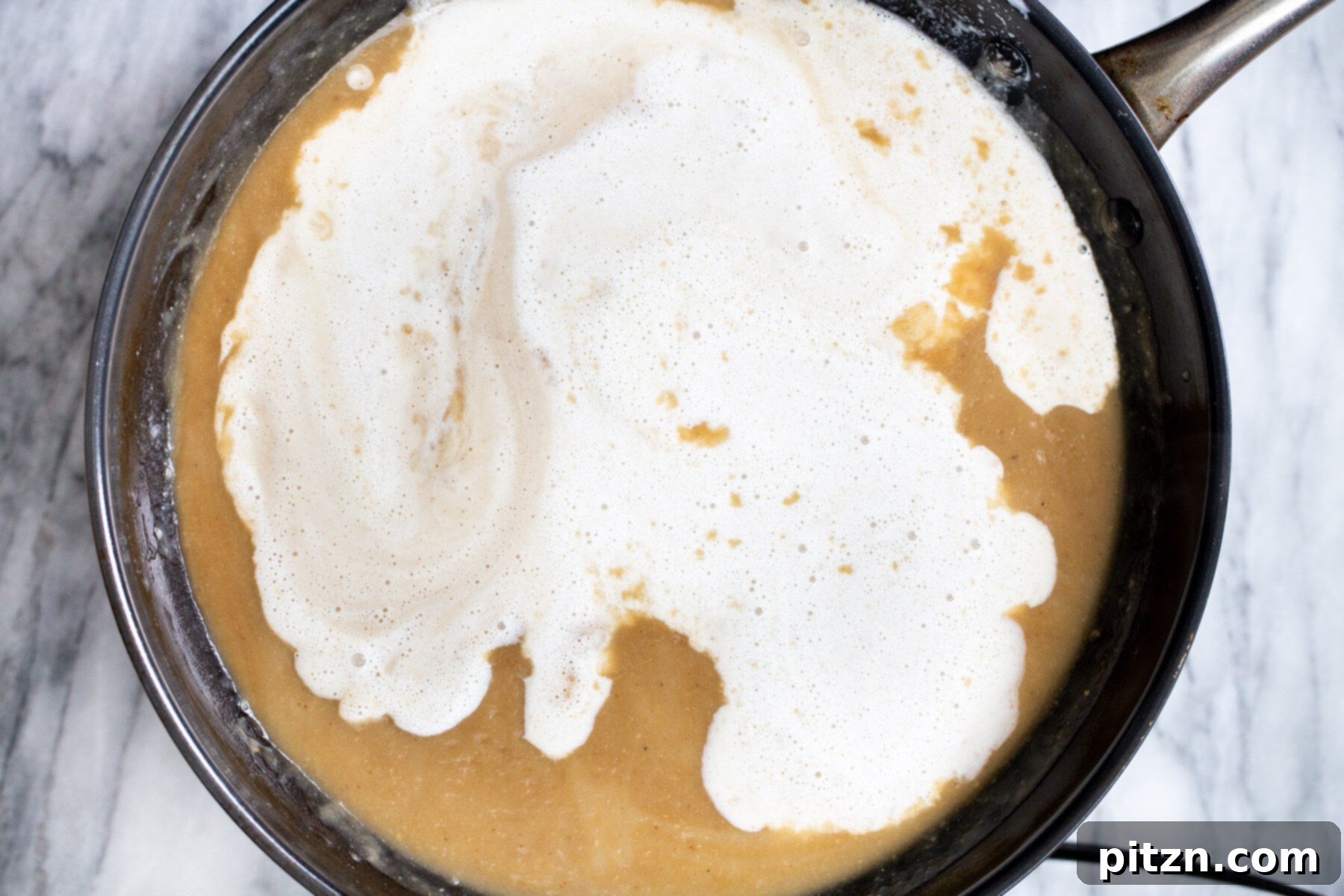Swedish Plant-Ball Perfection 17 Creamy cashew milk being added to the rich vegan mushroom gravy in a skillet.
