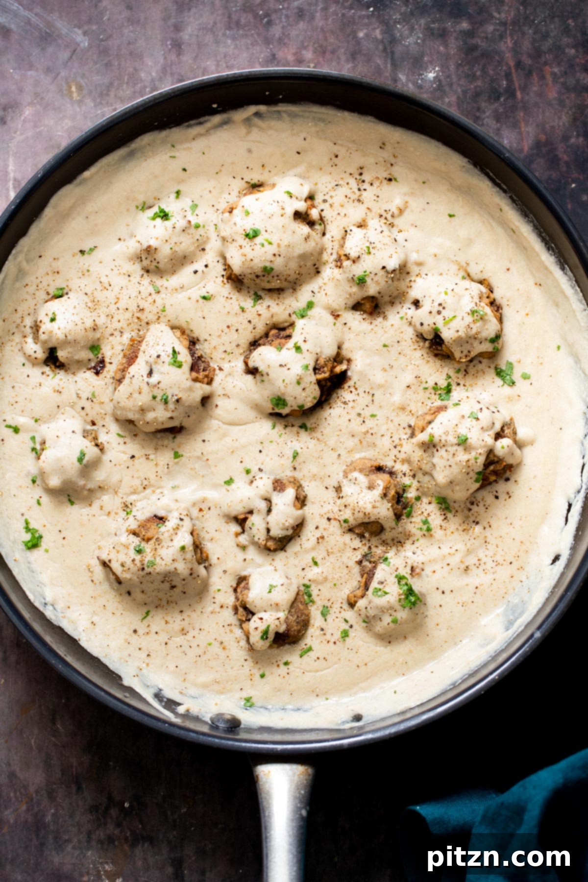 Swedish Plant-Ball Perfection 22 Vegan mushroom balls in a rich vegan mushroom gravy, served in a black saucepan, ready to be enjoyed.
