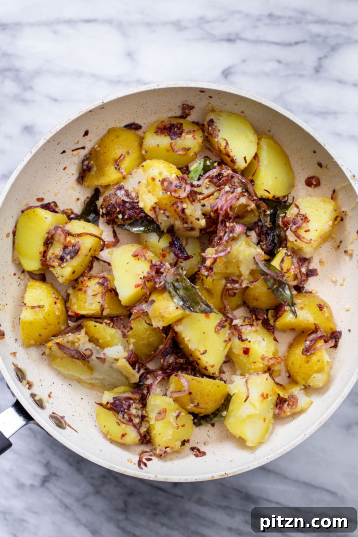 A vibrant and appetizing plate of South Indian Potato Pepper Stir-fry, highlighting the perfectly cooked onions and red potatoes, adorned with fresh cilantro.