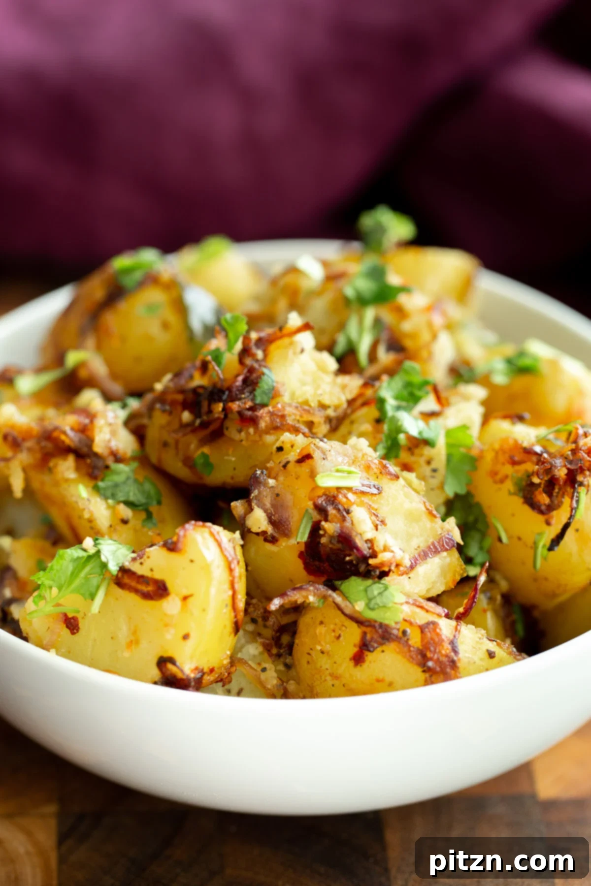 A close-up shot of a bowl filled with Indian potato pepper stir-fry, highlighting the tender potatoes, glistening mustard seeds, and vibrant curry leaves.