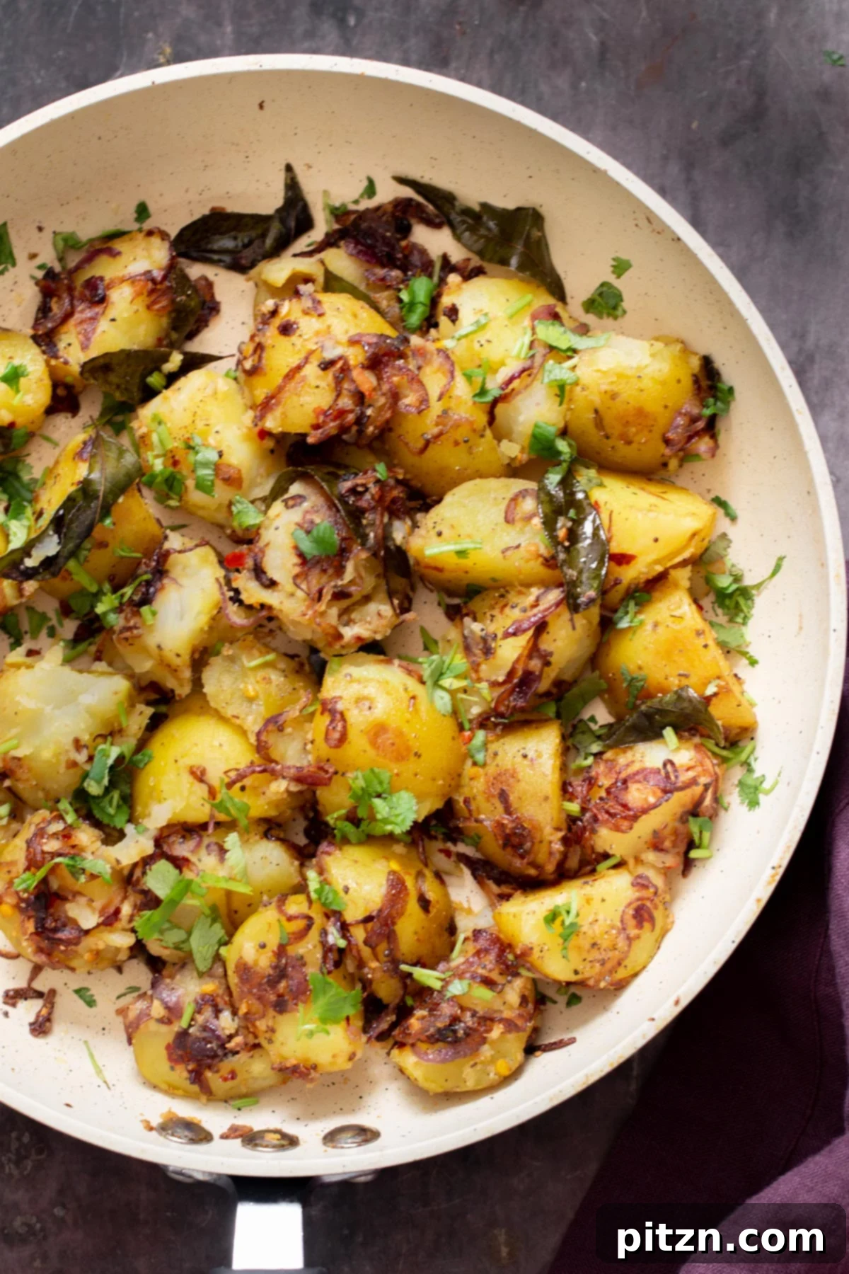 An overhead view of a skillet showcasing golden pan-fried potatoes and caramelized red onions, sprinkled with fresh green cilantro.