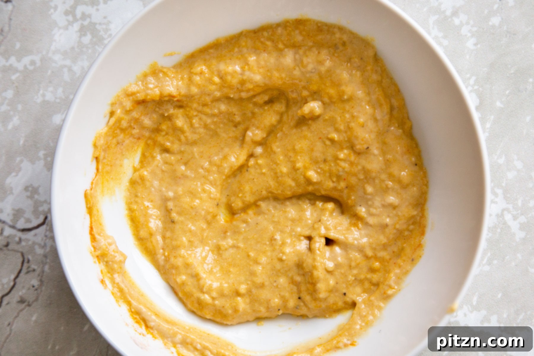 Smoky Tofu and Potato Sunrise Quesadillas 10 Creamy vegan eggy hummus, vibrant with turmeric, presented in a clean white bowl.