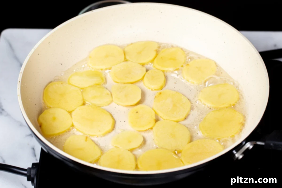 Smoky Tofu and Potato Sunrise Quesadillas 11 Thinly sliced potatoes being fried in a pan, turning golden brown.