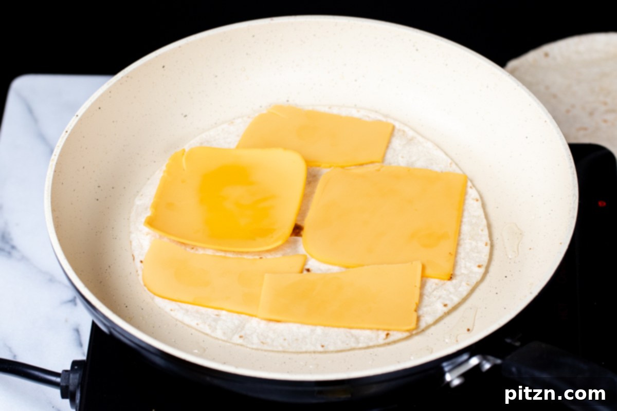 Smoky Tofu and Potato Sunrise Quesadillas 13 Vegan cheese slices being placed on a wheat tortilla in a pan, beginning the quesadilla assembly.