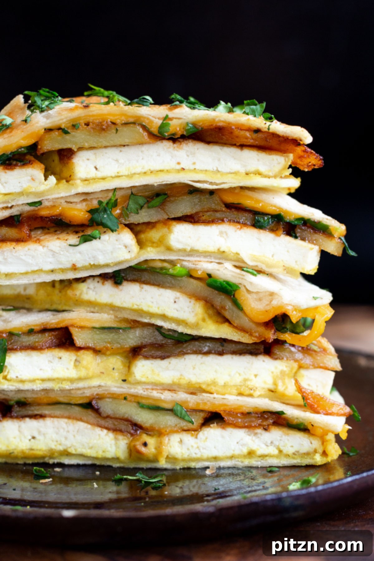 Smoky Tofu and Potato Sunrise Quesadillas 19 Stacked, sliced vegan breakfast quesadillas showing layers of tofu, smoky potatoes, eggy hummus, and melted vegan cheese.