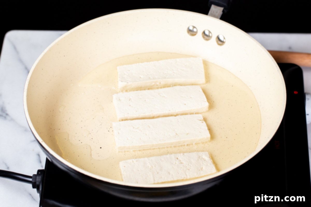 Smoky Tofu and Potato Sunrise Quesadillas 7 Tofu wedges being carefully added to a hot pan with oil, ready for pan-frying.