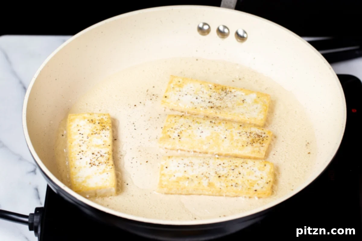 Smoky Tofu and Potato Sunrise Quesadillas 8 Close-up of perfectly pan-fried slices of tofu in a sautéing pan, showing their golden-brown edges.