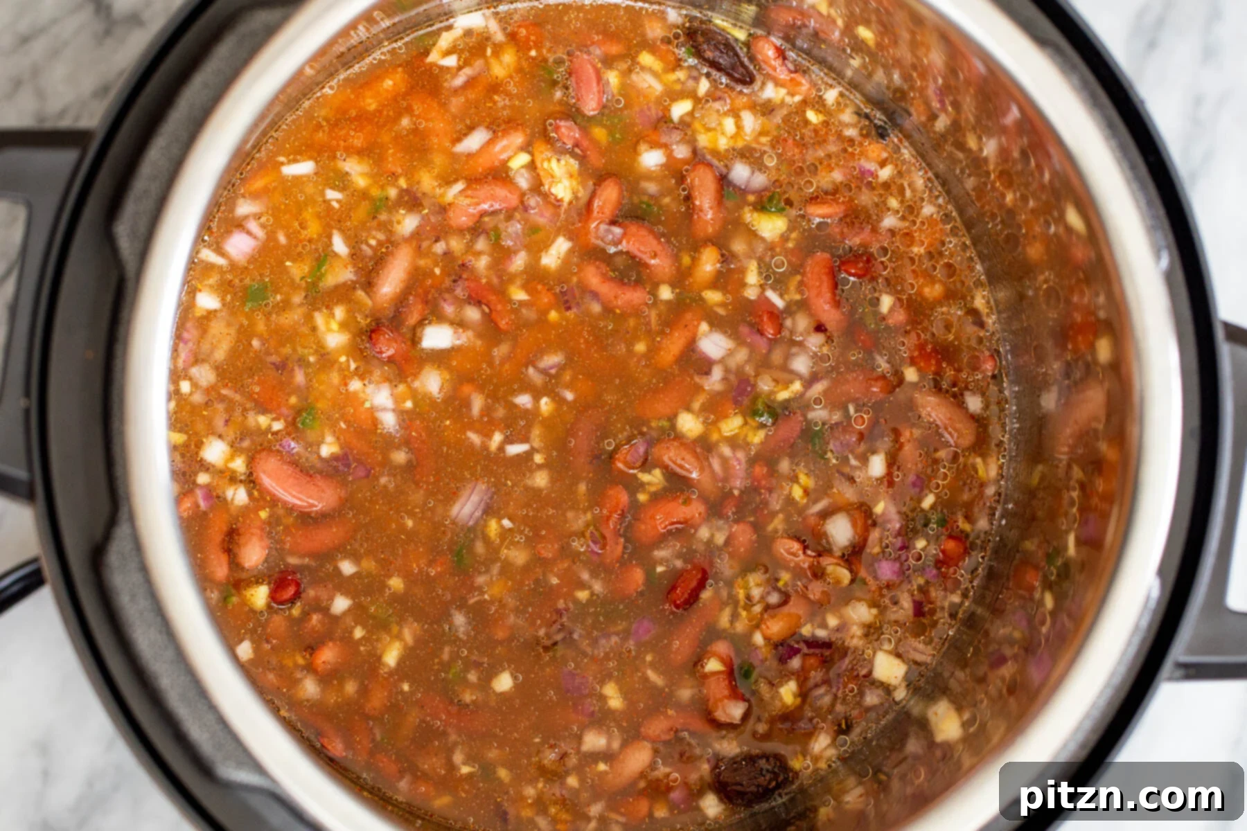Instant Pot Dhaba Rajma: Authentic & Easy Kidney Bean Curry 10 red kidney beans cooking with onion and tomato paste, simmering in an instant pot
