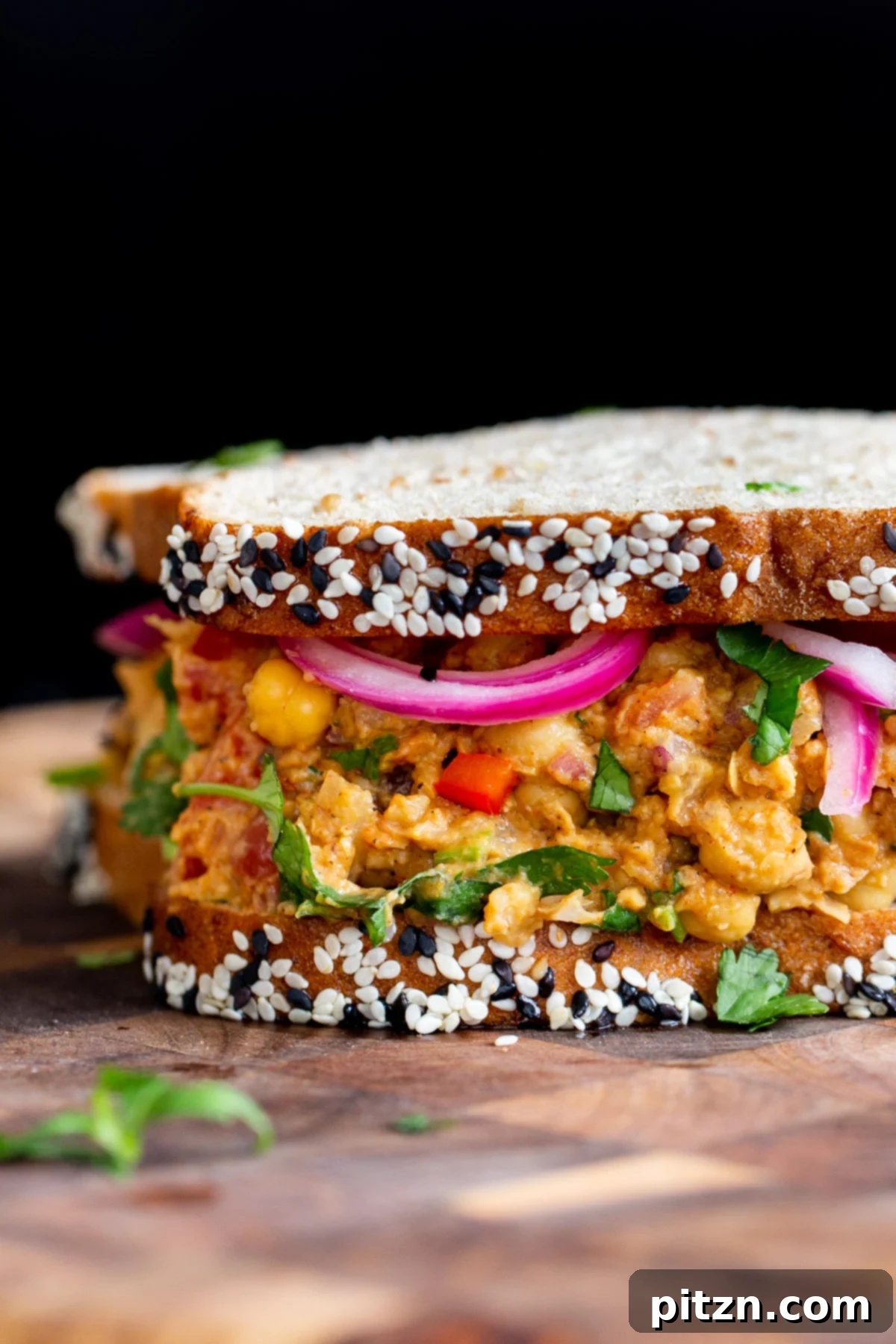 Close-up side view of a freshly prepared vegan lunch sandwich with curried chickpea salad filling, showcasing its creamy texture