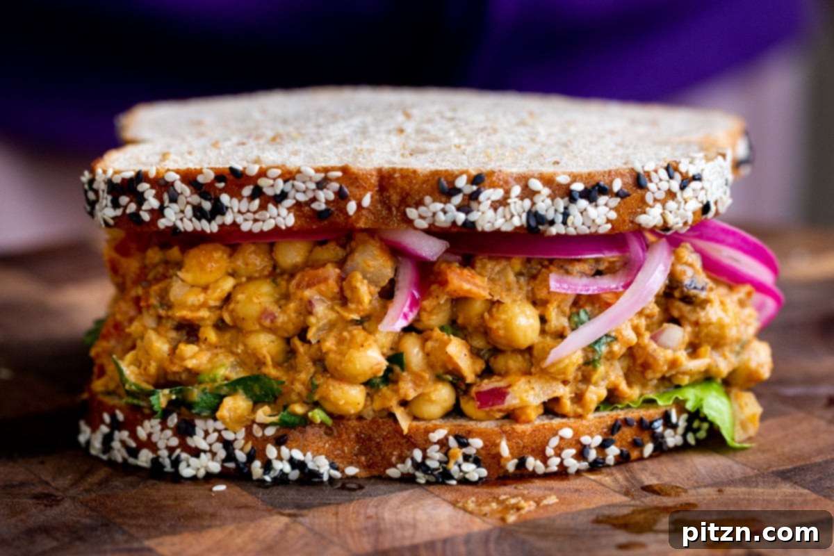 Side view of a healthy vegan curried chickpea salad sandwich on a rustic chopping board, ready to be served