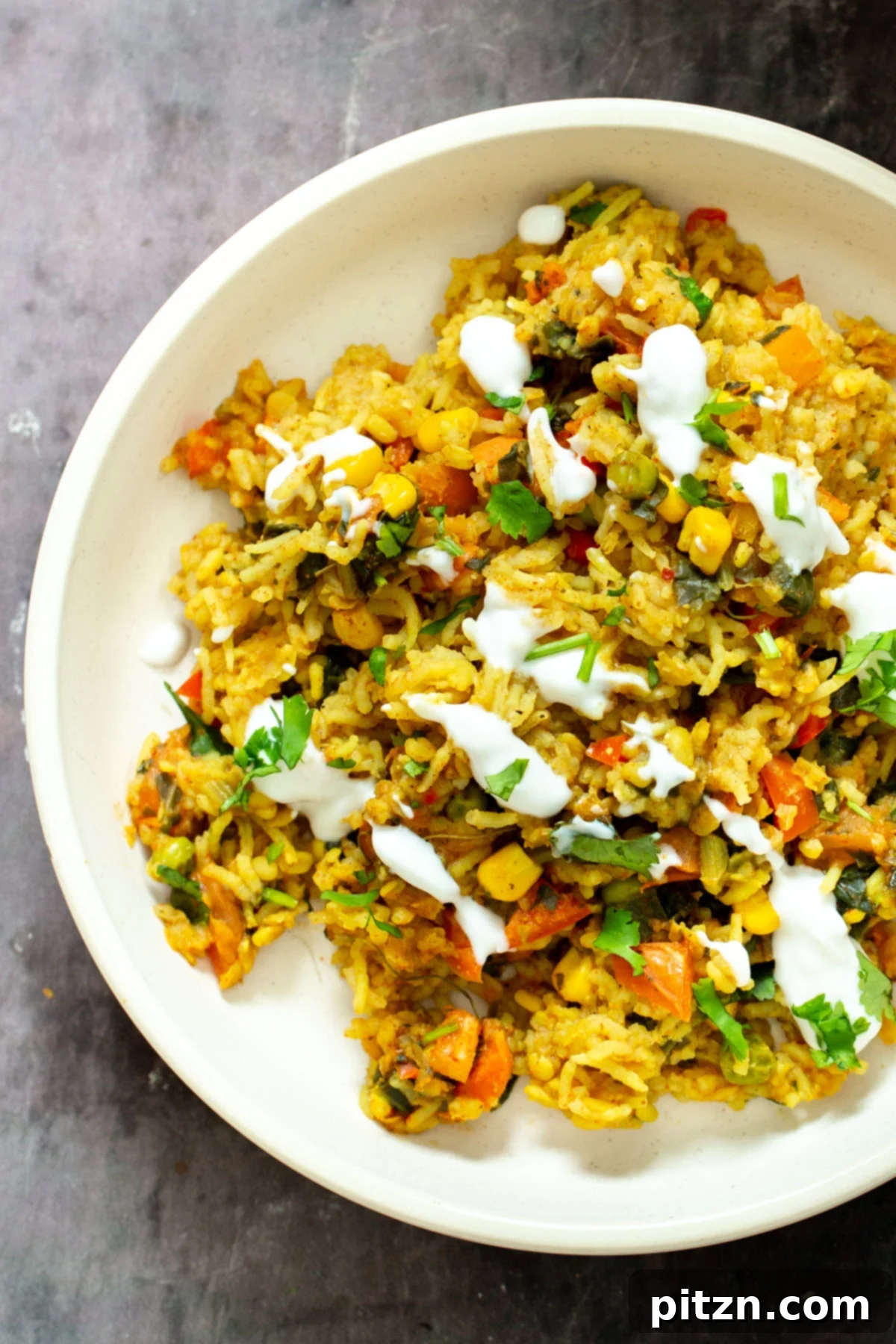 Spiced Kitchari Comfort Bake 5 A close-up view of a plate featuring Indian lentil rice casserole, generously drizzled with creamy vegan yogurt and garnished with fresh cilantro, highlighting its inviting texture and vibrant colors.