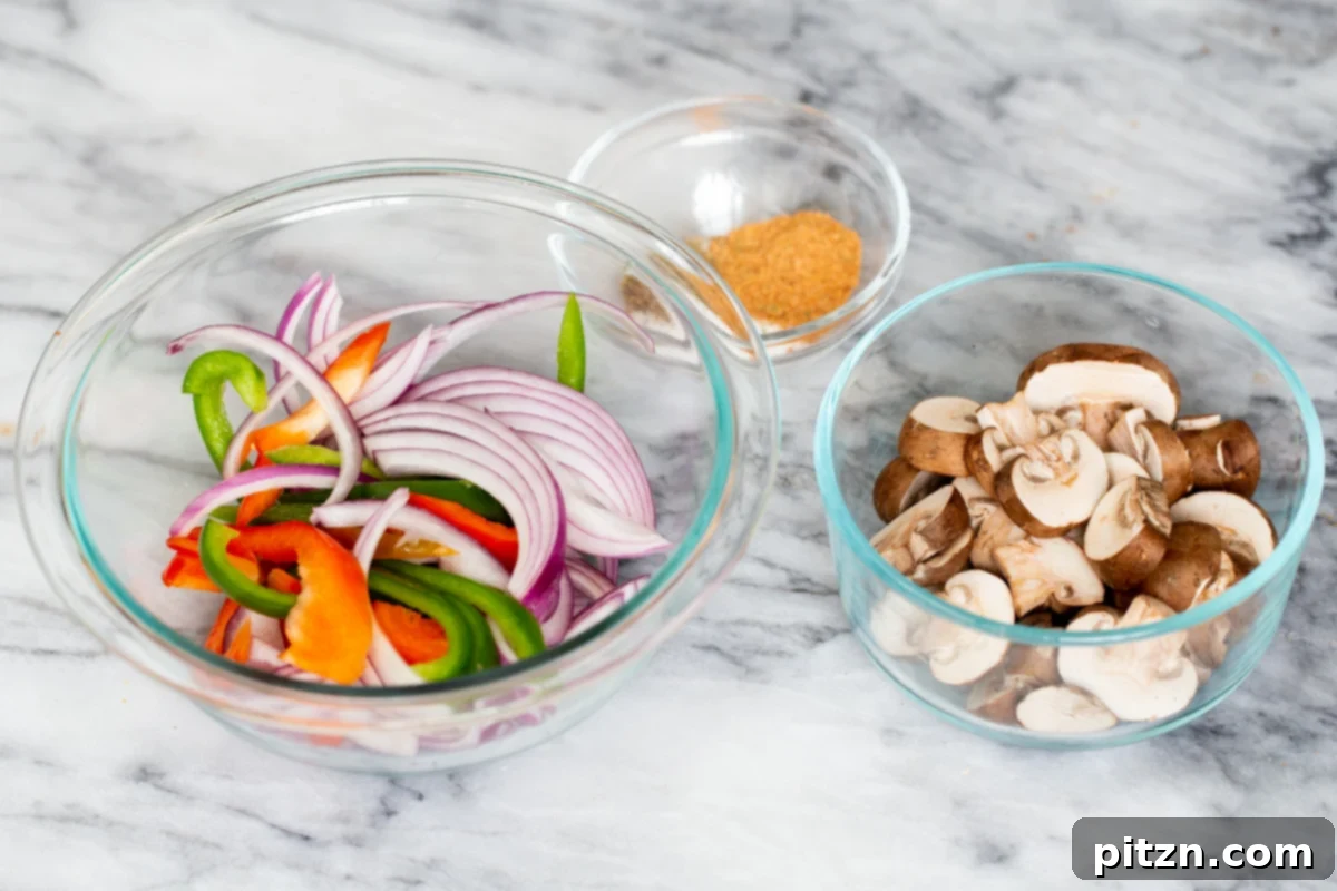 A selection of fresh, thinly sliced vegetables including mushrooms, green bell peppers, red bell peppers, and red onions, neatly arranged on a white marble countertop, ready for preparing the vegan birria filling.