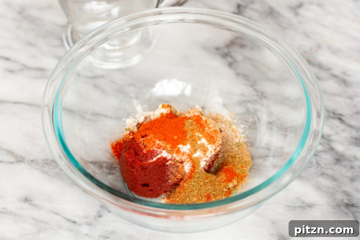 A small glass dish holds a colorful blend of ground spices, including turmeric, paprika, and garam masala, ready to be incorporated into the Tikka Masala sauce, promising rich and aromatic flavors.