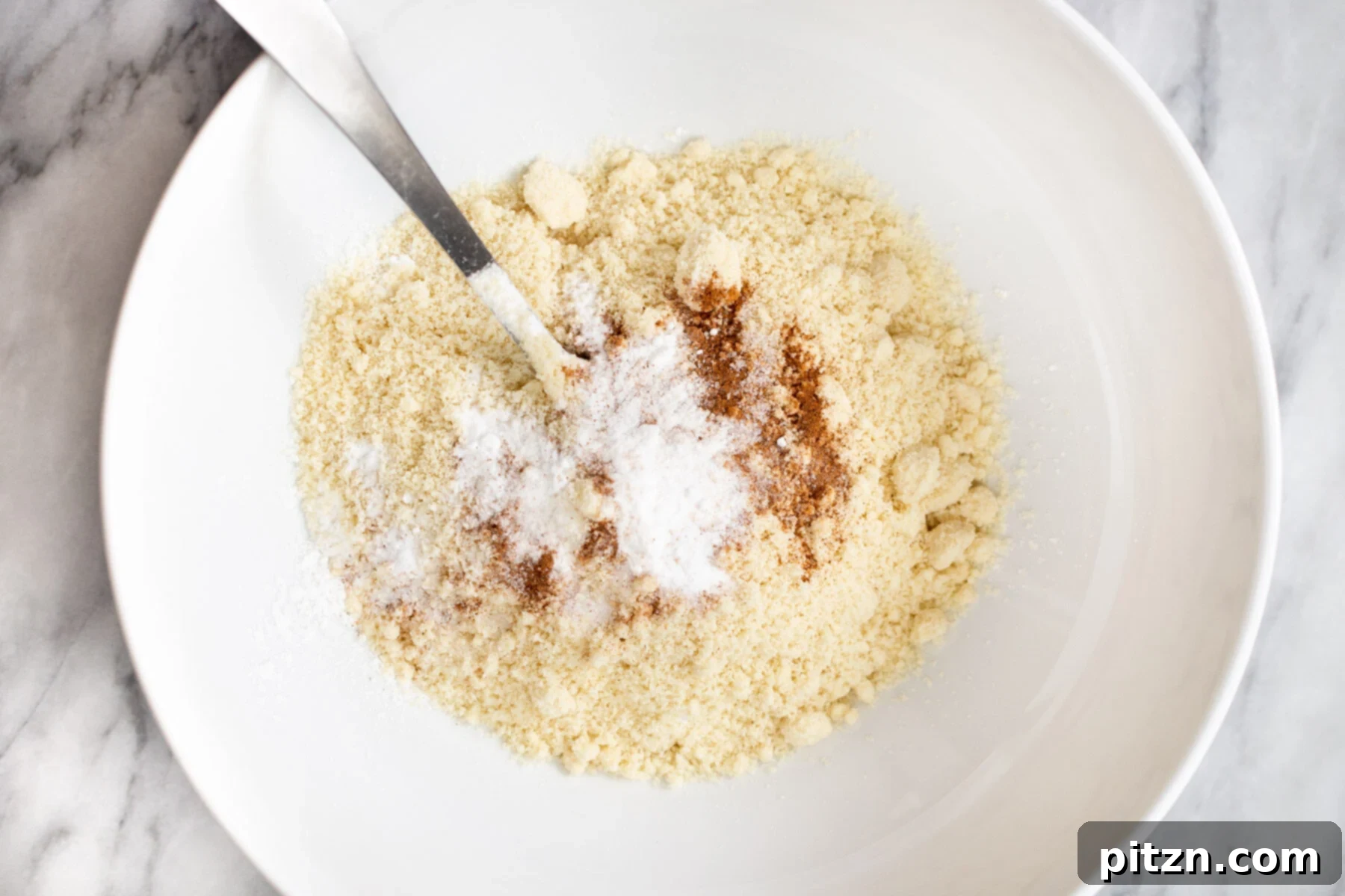 Soft and Chewy Gluten-Free Almond Flour Snickerdoodles 7 Dry ingredients for vegan snickerdoodles meticulously measured and combined in a pristine white bowl, ready for mixing.