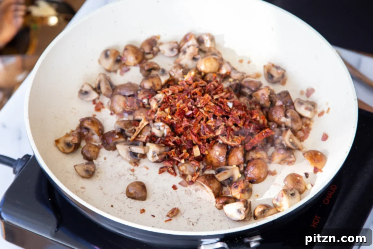 Creamy Vegan One-Pot Pasta: Mushrooms & Sun-Dried Tomatoes 11 Chopped sun-dried tomatoes being added to the sautéing pan with mushrooms, onions, and garlic.
