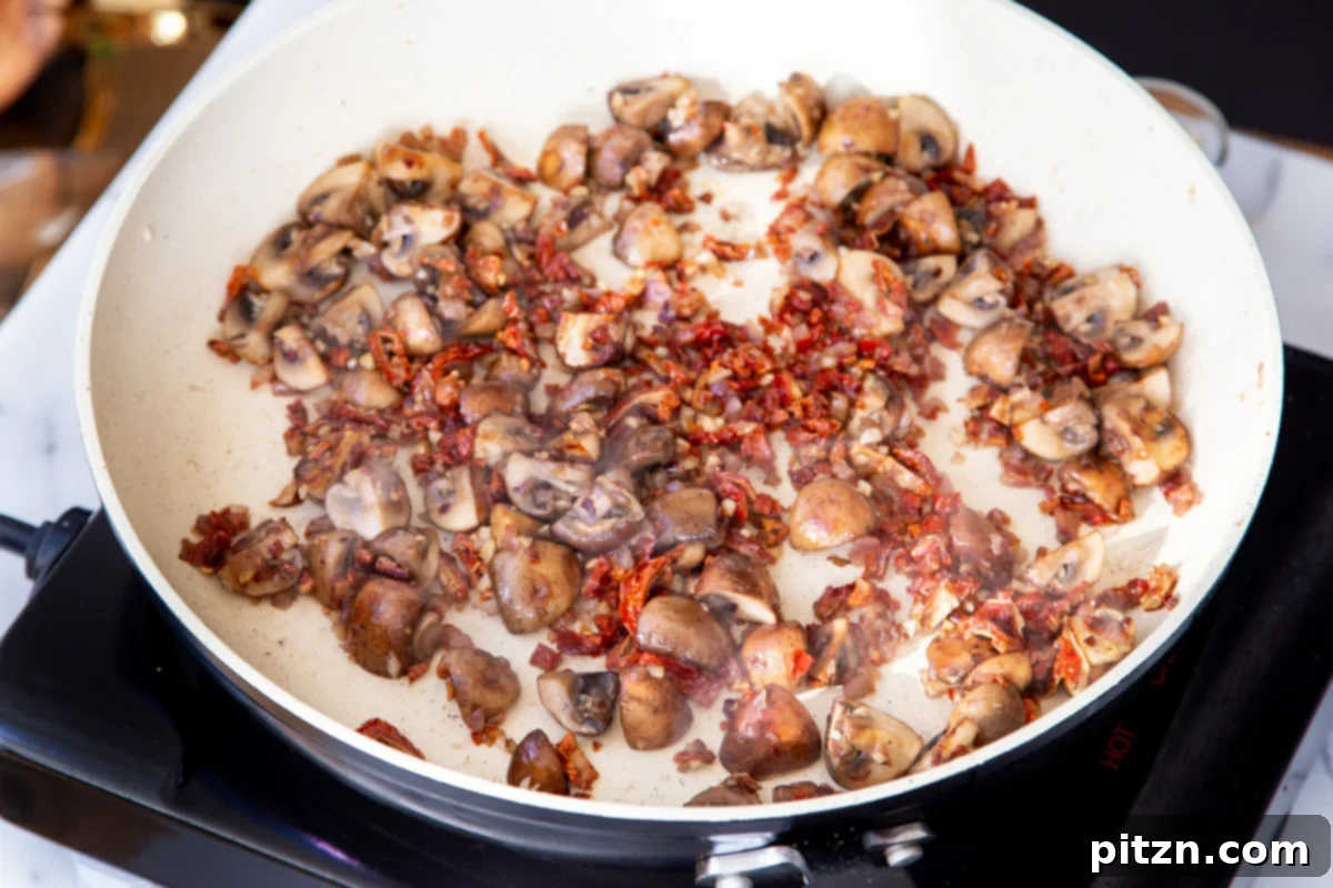 Creamy Vegan One-Pot Pasta: Mushrooms & Sun-Dried Tomatoes 12 Sautéed mushrooms and sun-dried tomatoes simmering together in a frying pan, creating a rich base for the pasta.