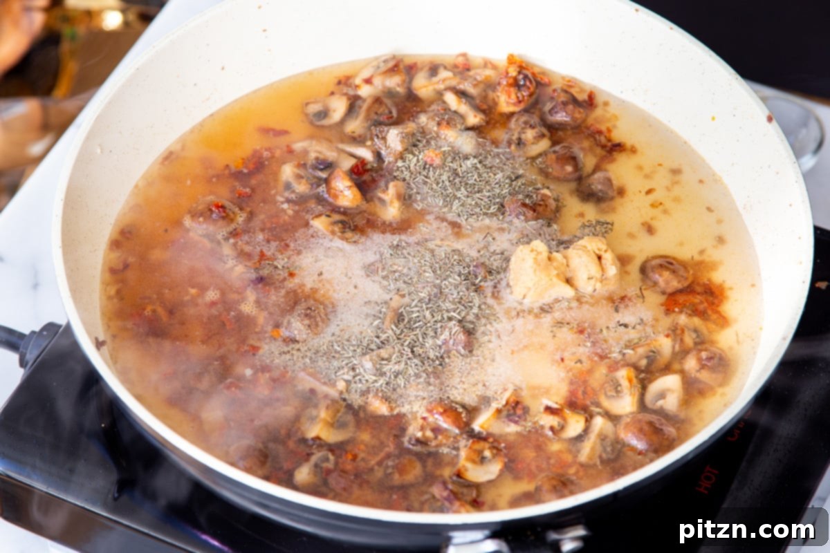 Creamy Vegan One-Pot Pasta: Mushrooms & Sun-Dried Tomatoes 13 Mushrooms and sun-dried tomatoes simmering in a flavorful liquid, creating the base for the pasta sauce.