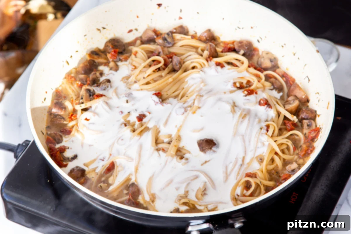 Creamy Vegan One-Pot Pasta: Mushrooms & Sun-Dried Tomatoes 17 Silky smooth cashew cream being poured into the one-pot mushroom and sun-dried tomato pasta, ready to create a creamy sauce.