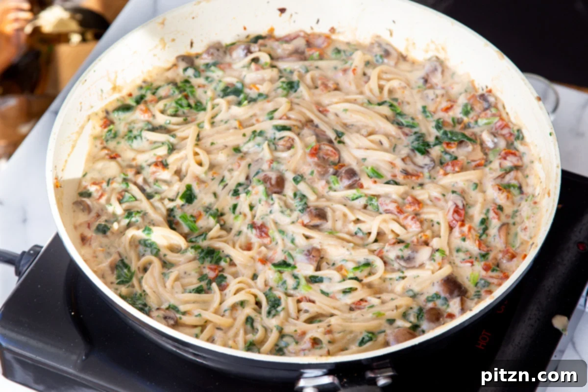 Creamy Vegan One-Pot Pasta: Mushrooms & Sun-Dried Tomatoes 19 Creamy spinach, mushroom, and sun-dried tomato pasta simmering gently in a saucepan, its sauce perfectly thickened and ready.