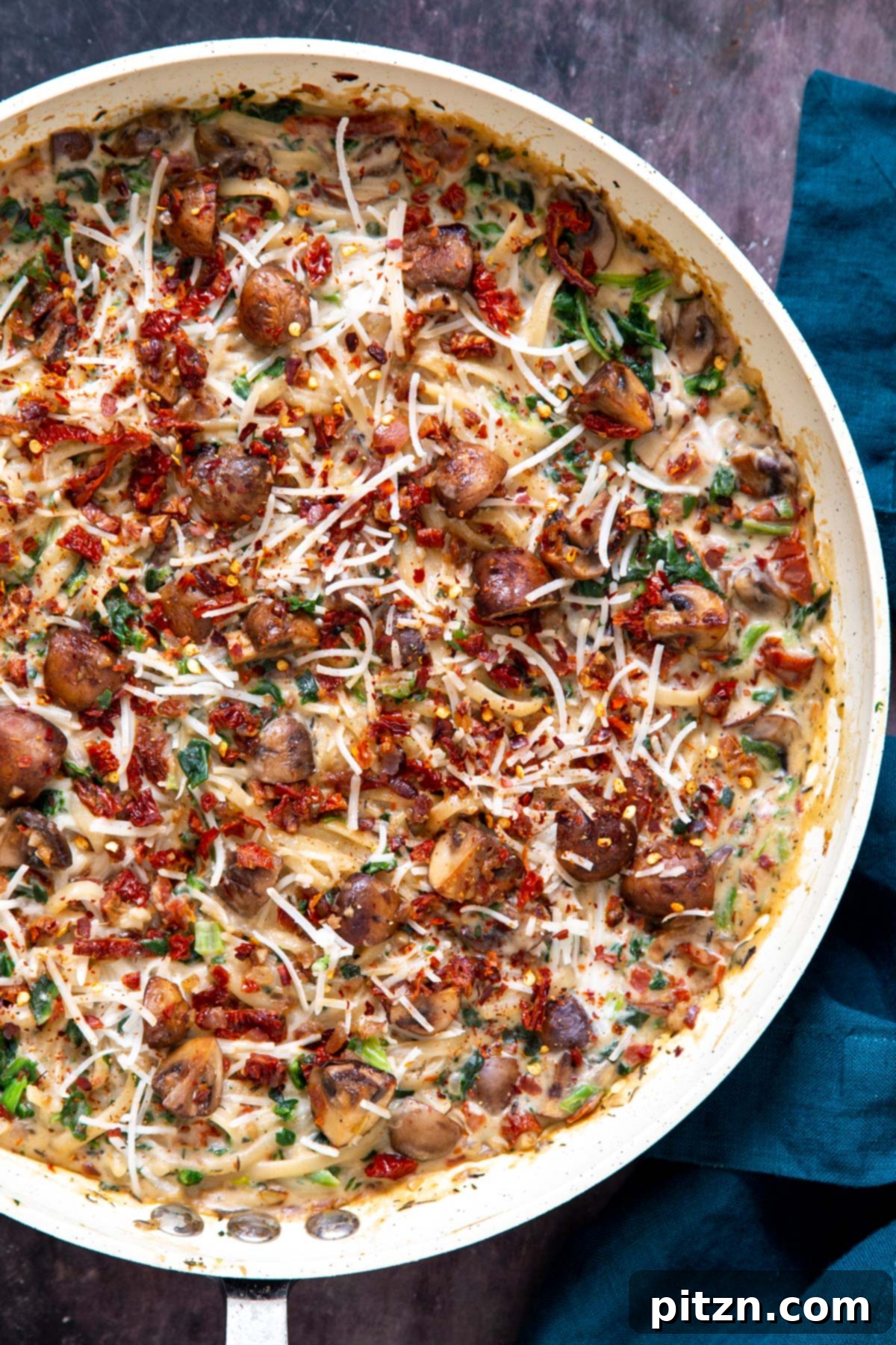 Creamy Vegan One-Pot Pasta: Mushrooms & Sun-Dried Tomatoes 4 Overhead shot of a saucepan filled with creamy vegan mushroom pasta, vibrant with spinach and sun-dried tomatoes, ready to be served.