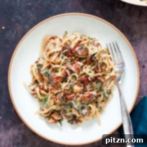 A beautifully plated portion of One Pot Creamy Mushroom Sun-dried Tomato Fettuccine, garnished for serving.