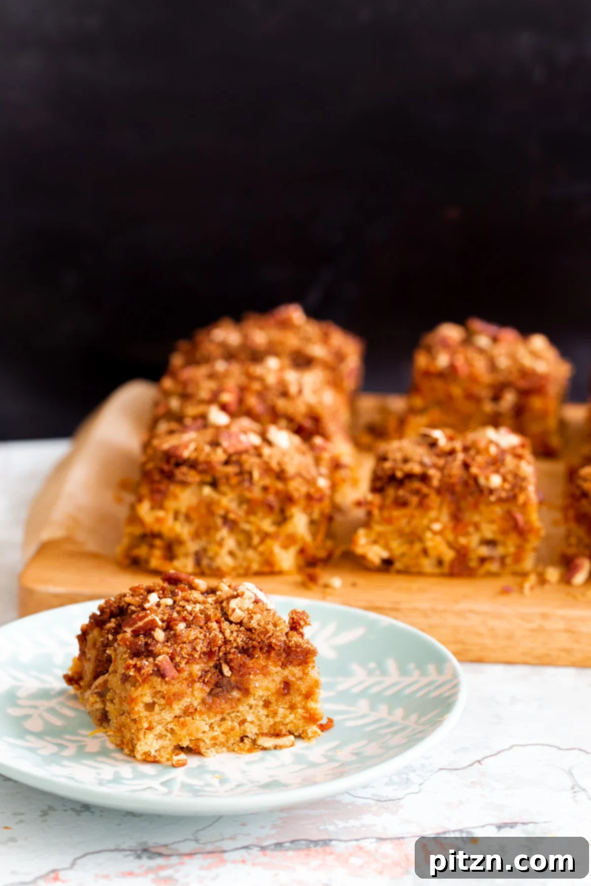 Spiced Vegan Carrot Cake Squares 23 A square slice of vegan carrot cake bar on a white and blue cake plate