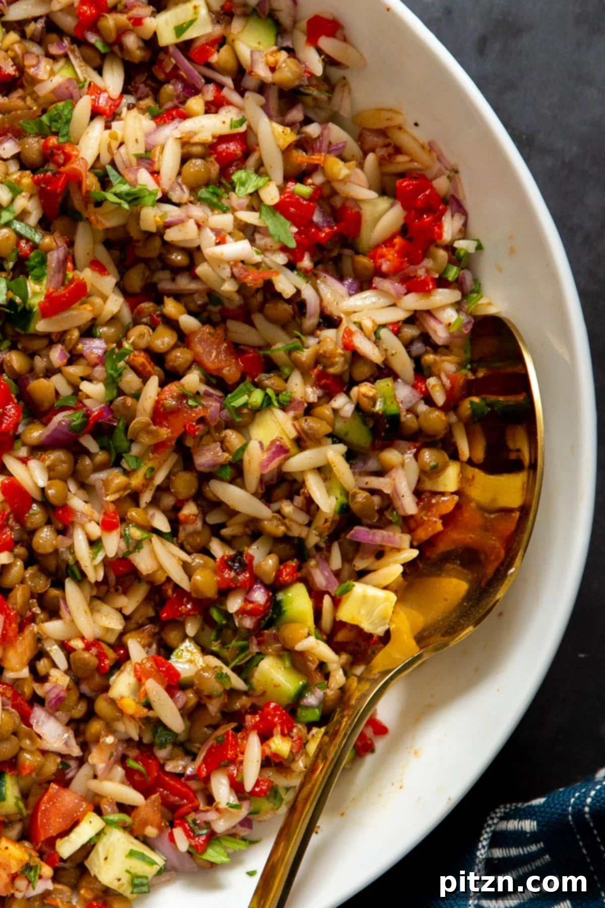 A bowl of vegan lentil farro salad with finely chopped fresh vegetables, glistening with a vibrant lemon vinaigrette, highlighting its fresh appeal.