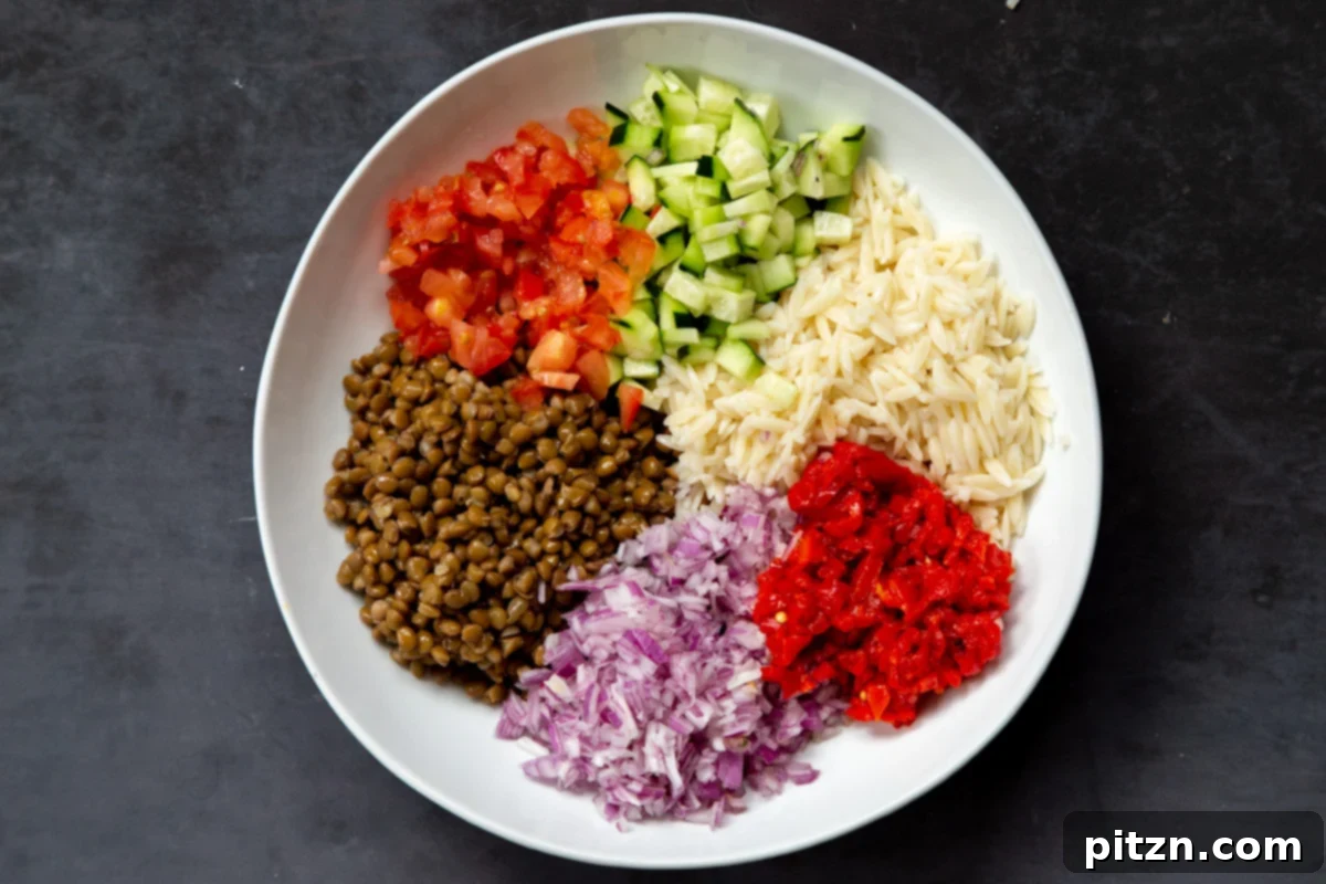 All the vibrant ingredients for the lentil farro salad are artfully arranged in a large white bowl, ready for mixing.