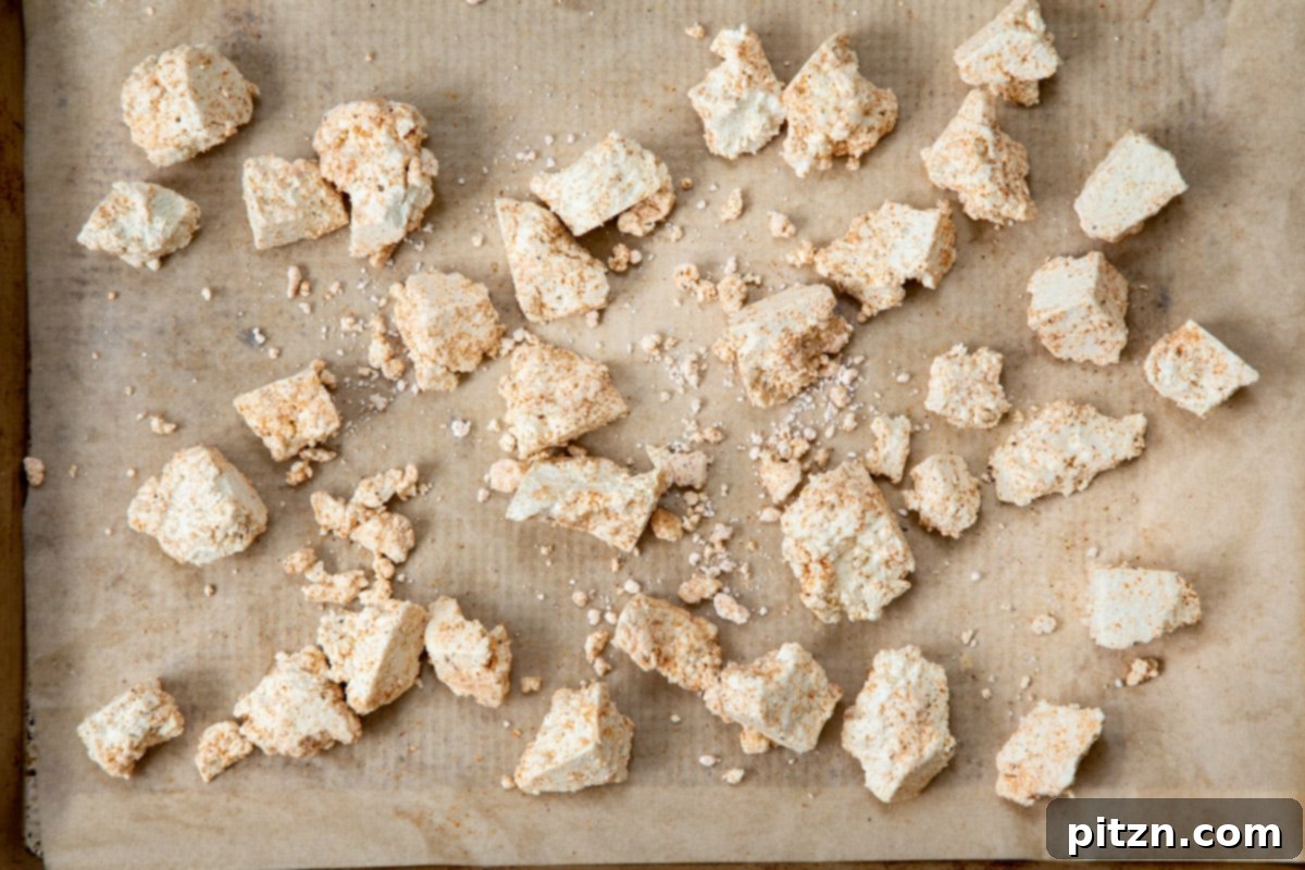 Coated pieces of seasoned tofu arranged neatly on a parchment-lined baking sheet, ready for the oven.