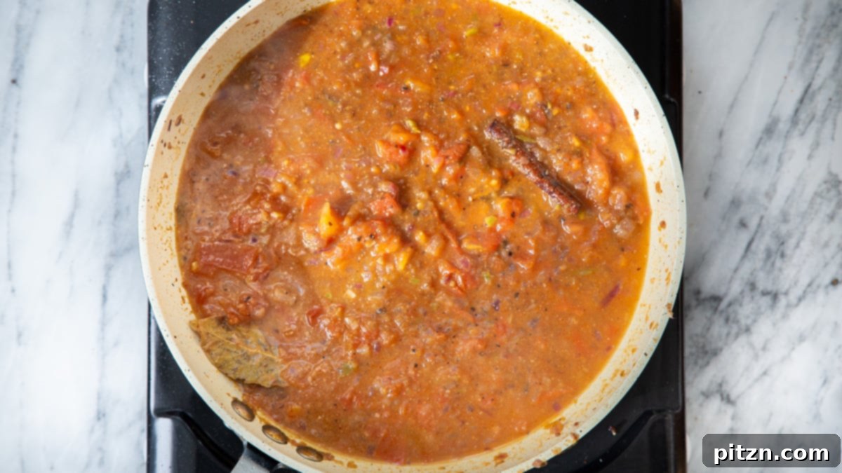 A close-up view of the vegan gravy for Khada Masala Murg, simmering robustly in a frying pan.