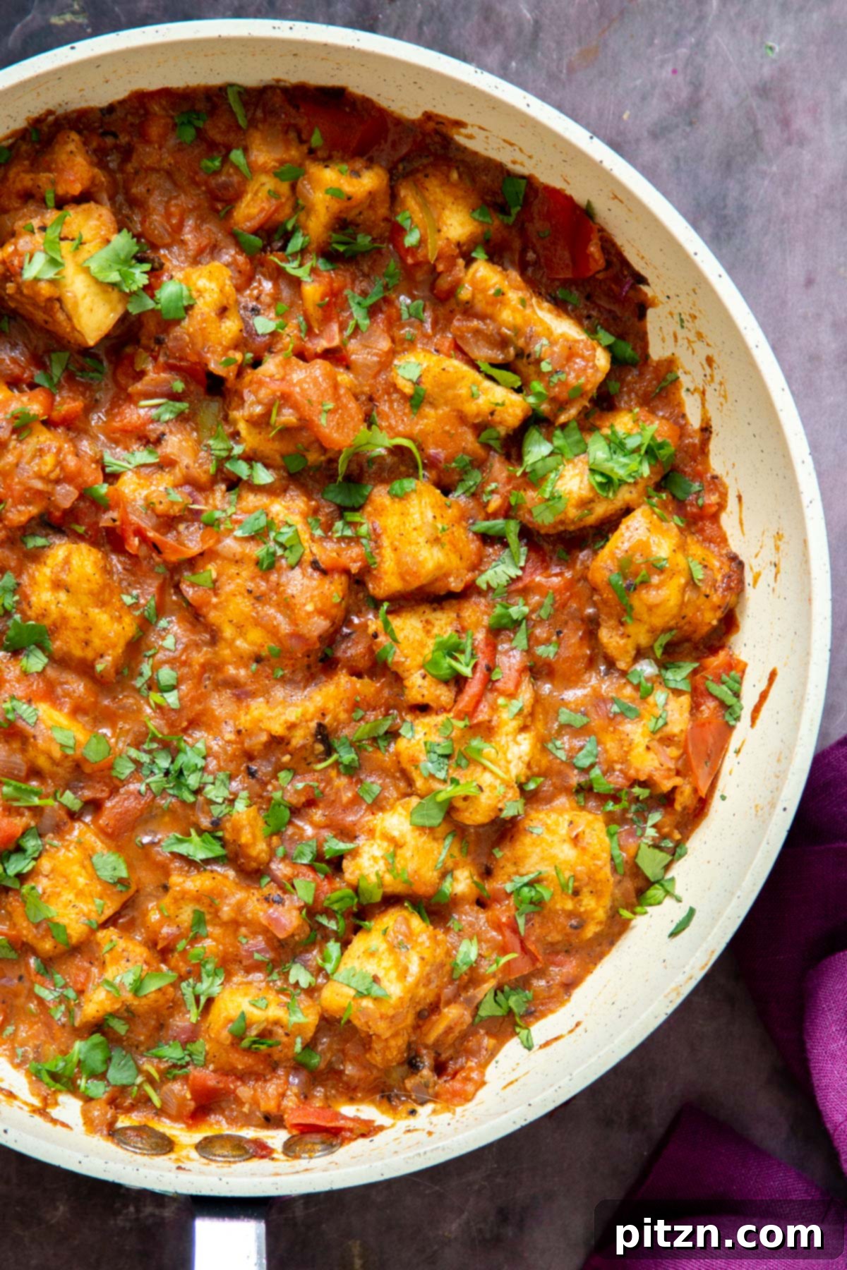 A pan brimming with Vegan Khada Masala Murg Curry, featuring crispy baked tofu, generously sprinkled with fresh, chopped cilantro, ready to be served.