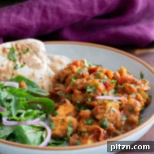 A top-down view of the Khada Masala Murg Curry with Baked Tofu, garnished with fresh cilantro, ready to be served.