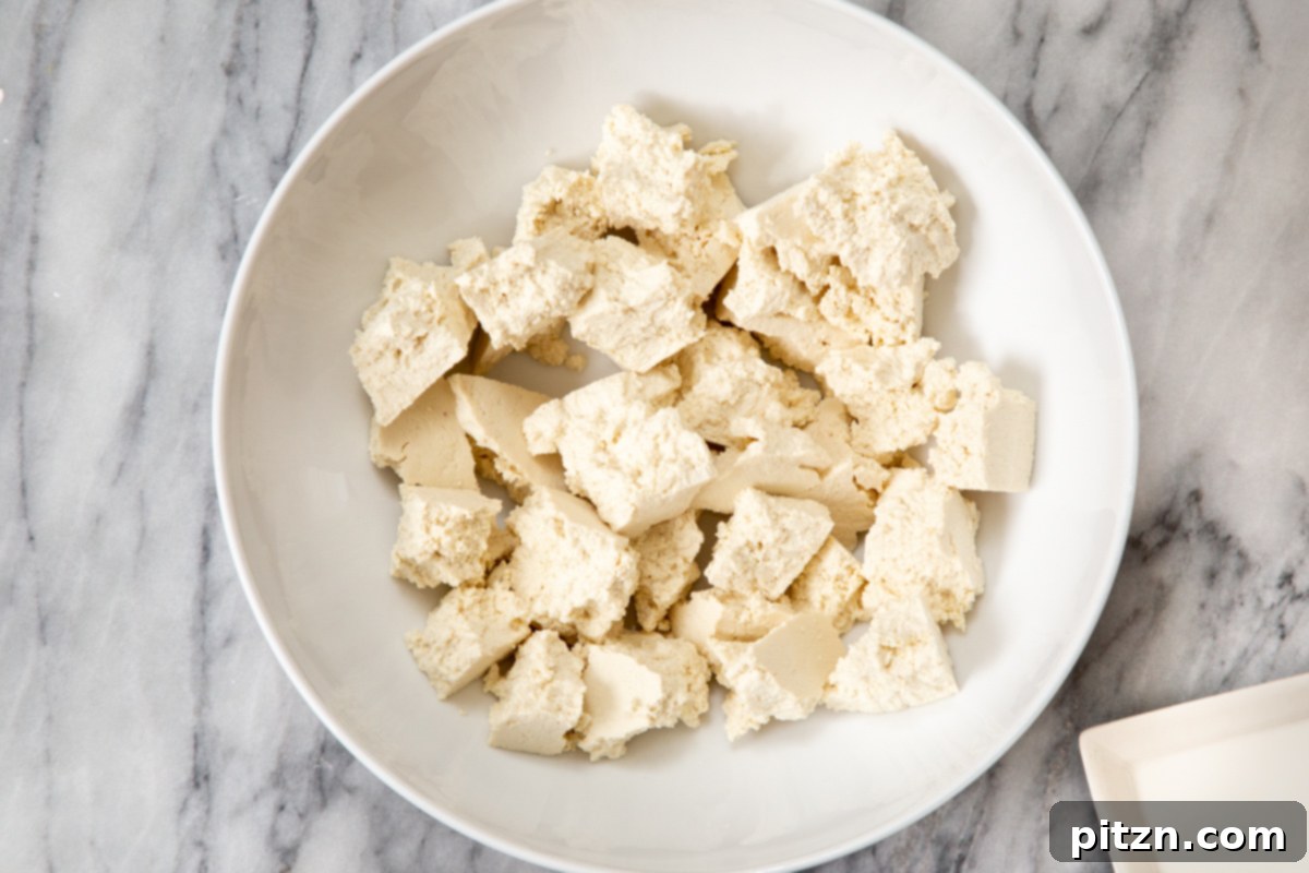 Pieces of torn, firm tofu resting in a clean white bowl, ready for seasoning.
