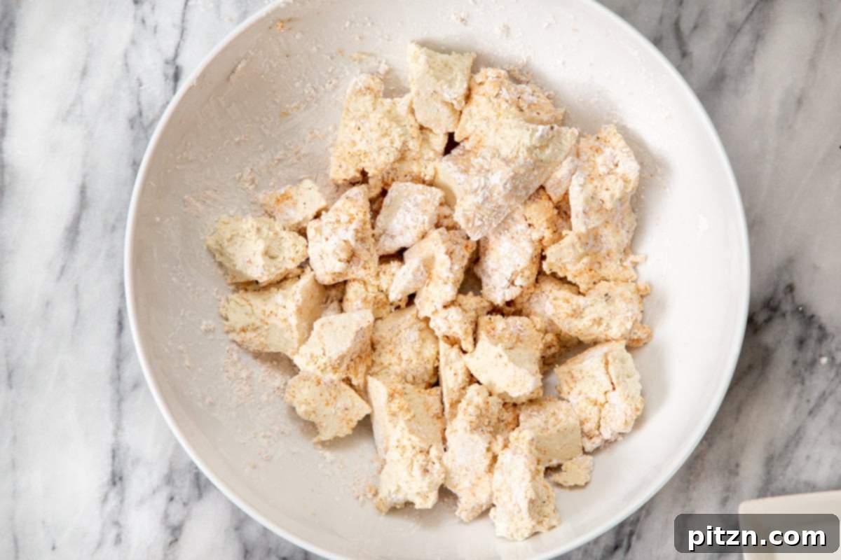 Torn firm tofu pieces evenly coated with a mixture of spices and cornstarch, glistening with flavor.