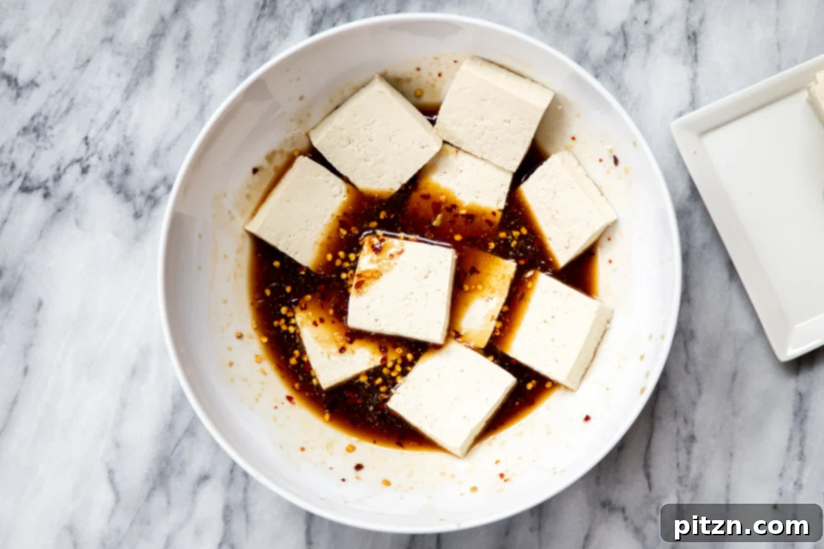 sliced tofu being added to a bowl with marinade