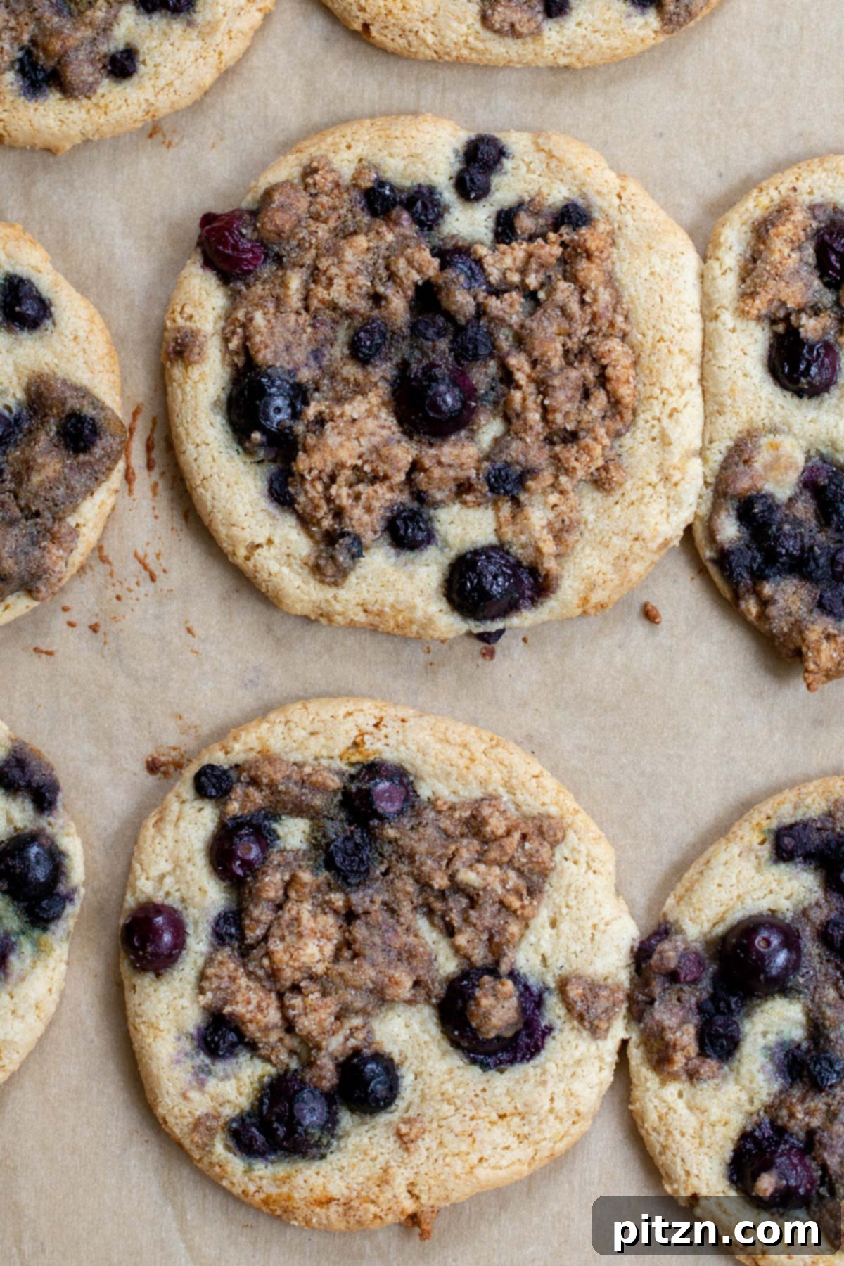 Gluten-Free Vegan Blueberry Muffin Cookies 17 Overhead shot of freshly baked Vegan Blueberry Muffin Cookies on a lined baking sheet, beautifully golden with scattered blueberries and streusel. Gluten-Free perfection.