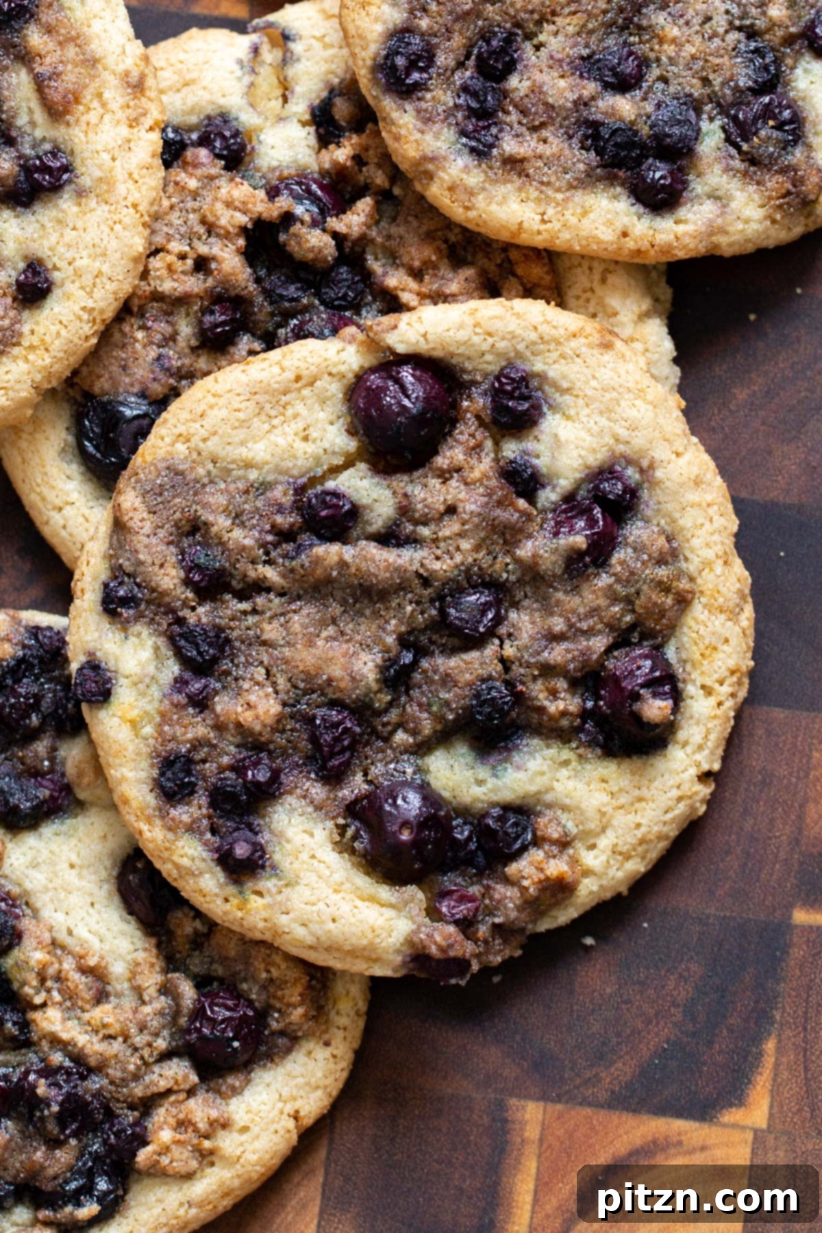 Gluten-Free Vegan Blueberry Muffin Cookies 3 Close-up view of two Vegan Blueberry Muffin Cookies on a wooden board, showcasing their rich blueberry filling and delicate streusel crumb. Ideal for a Gluten-Free, Vegan lifestyle.