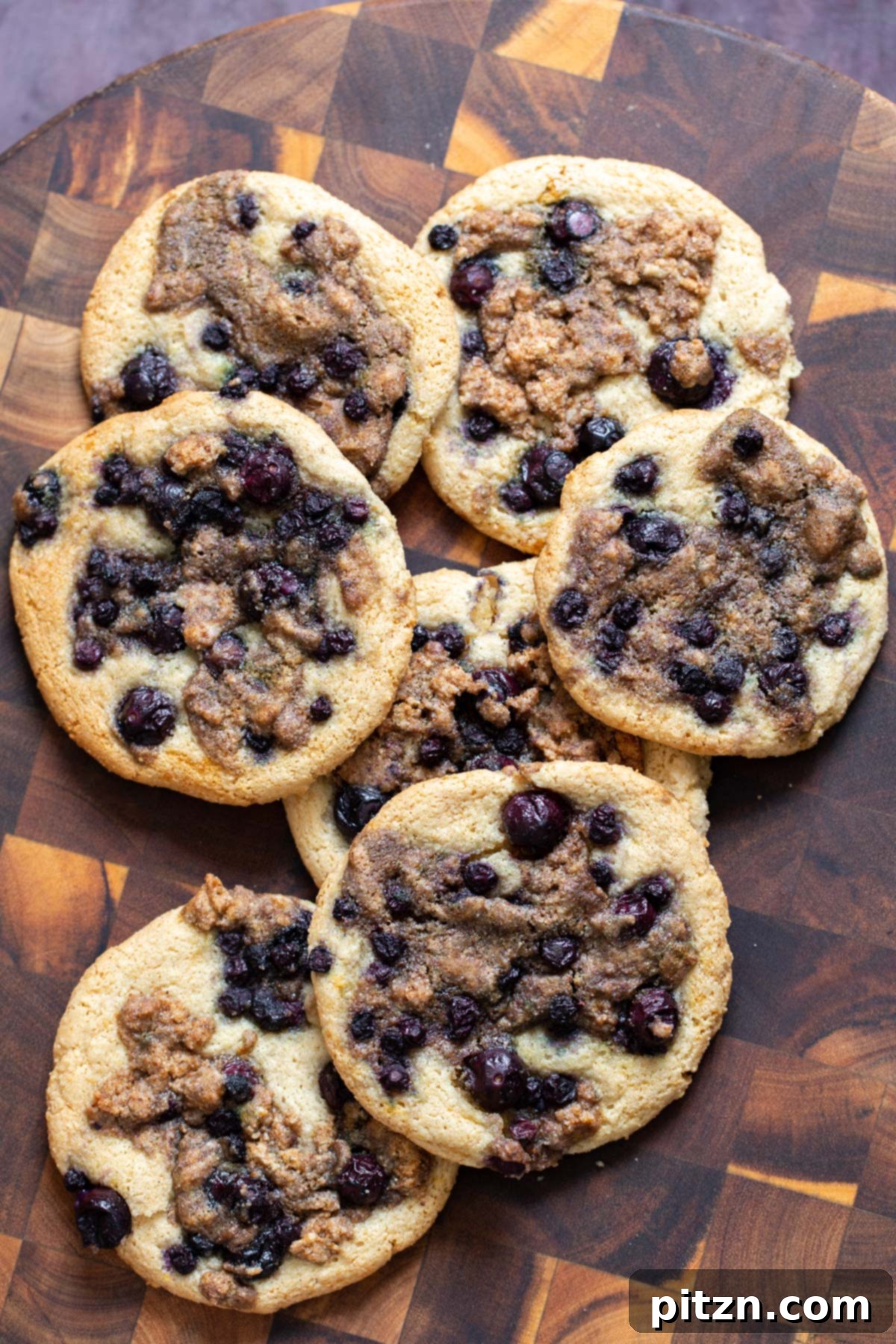 Gluten-Free Vegan Blueberry Muffin Cookies 4 A small stack of freshly baked Vegan Blueberry Muffin Cookies, garnished with a sprig of mint, on a chopping board. These Grain-Free Almond Flour Cookies are a wholesome treat.