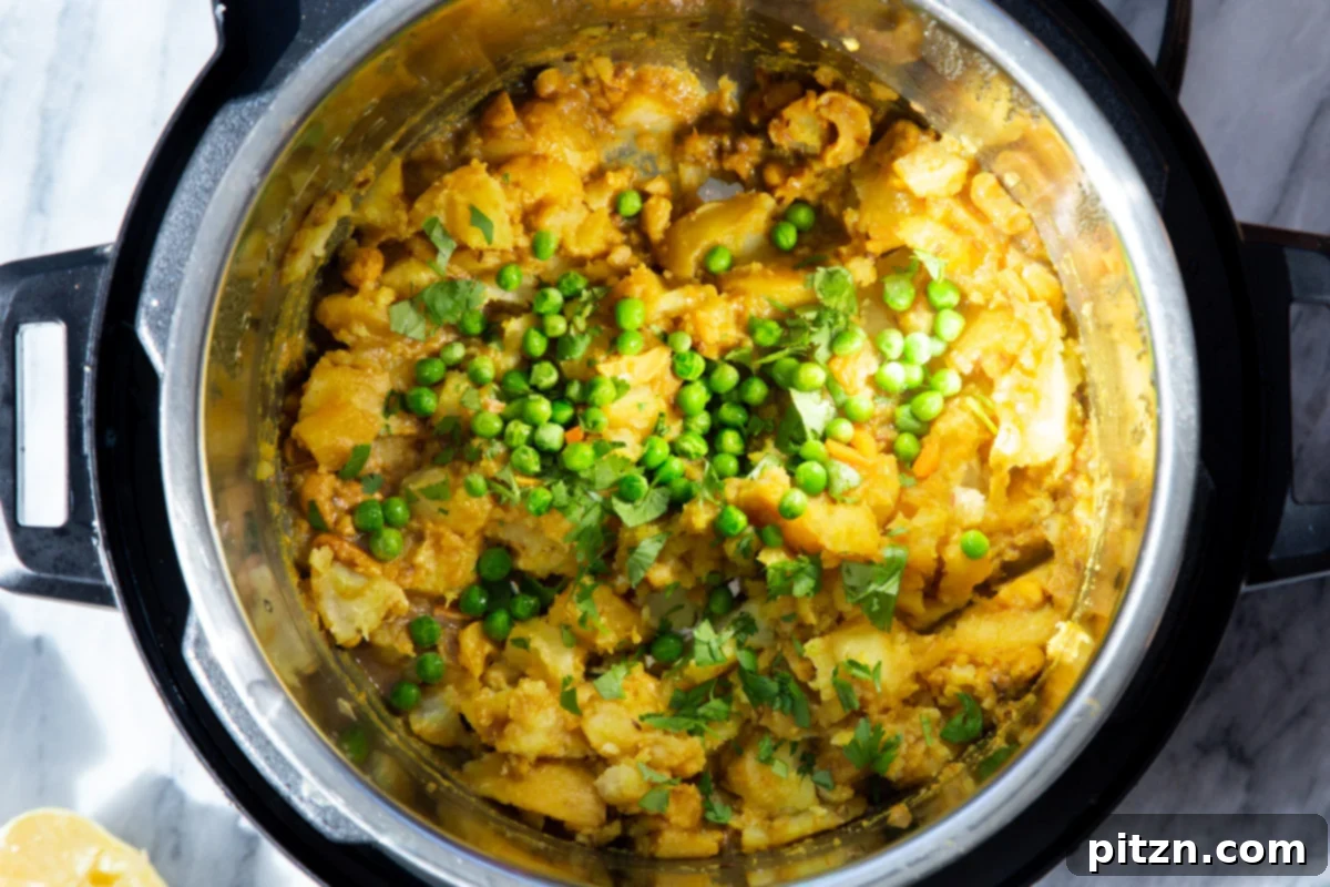 Fresh peas and cilantro being incorporated into the hot potato mixture in an Instant Pot, adding vibrant color and flavor to the pie filling.