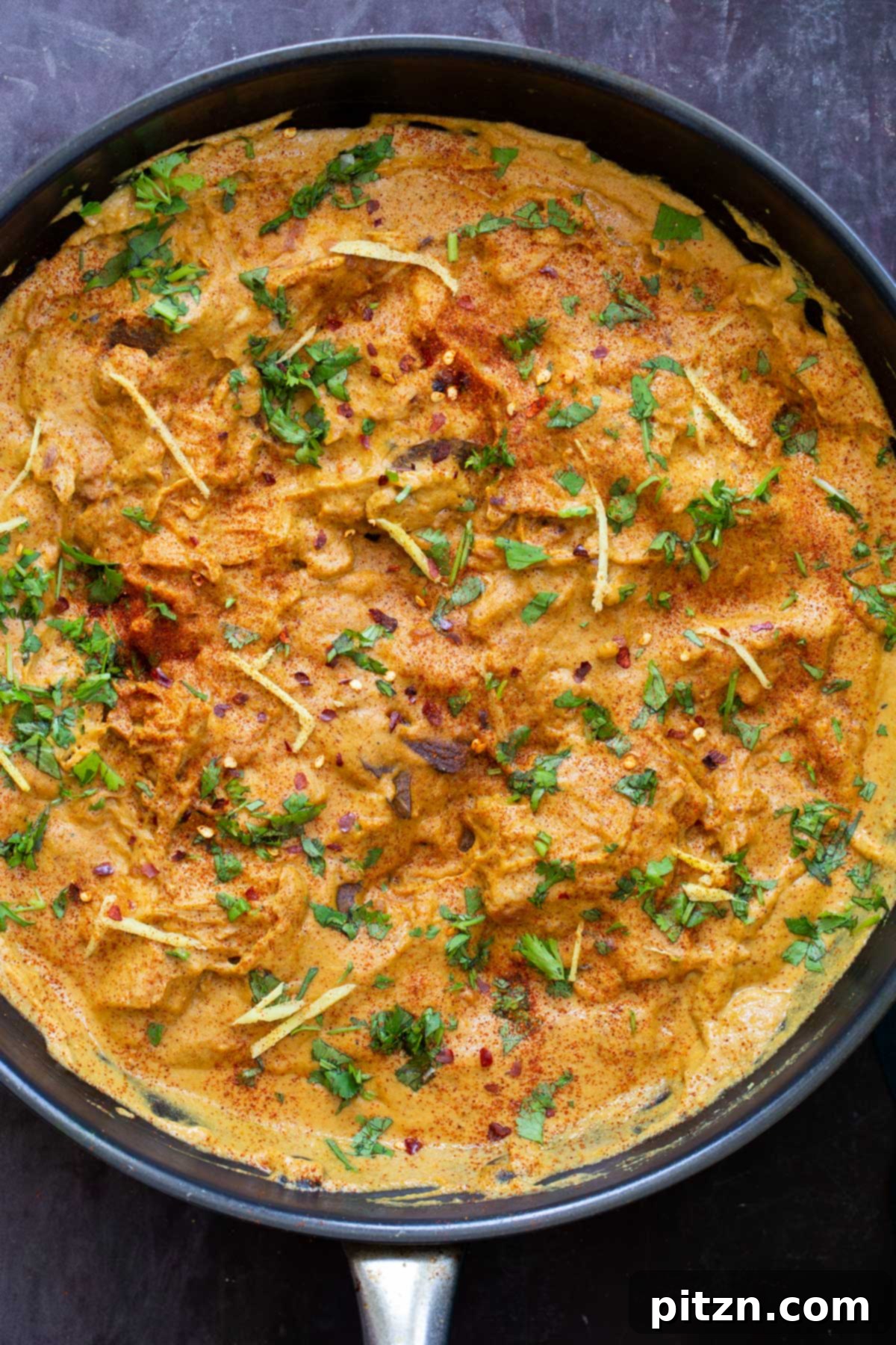 a black skillet with vegan jackfruit korma sprinkled with herbs 